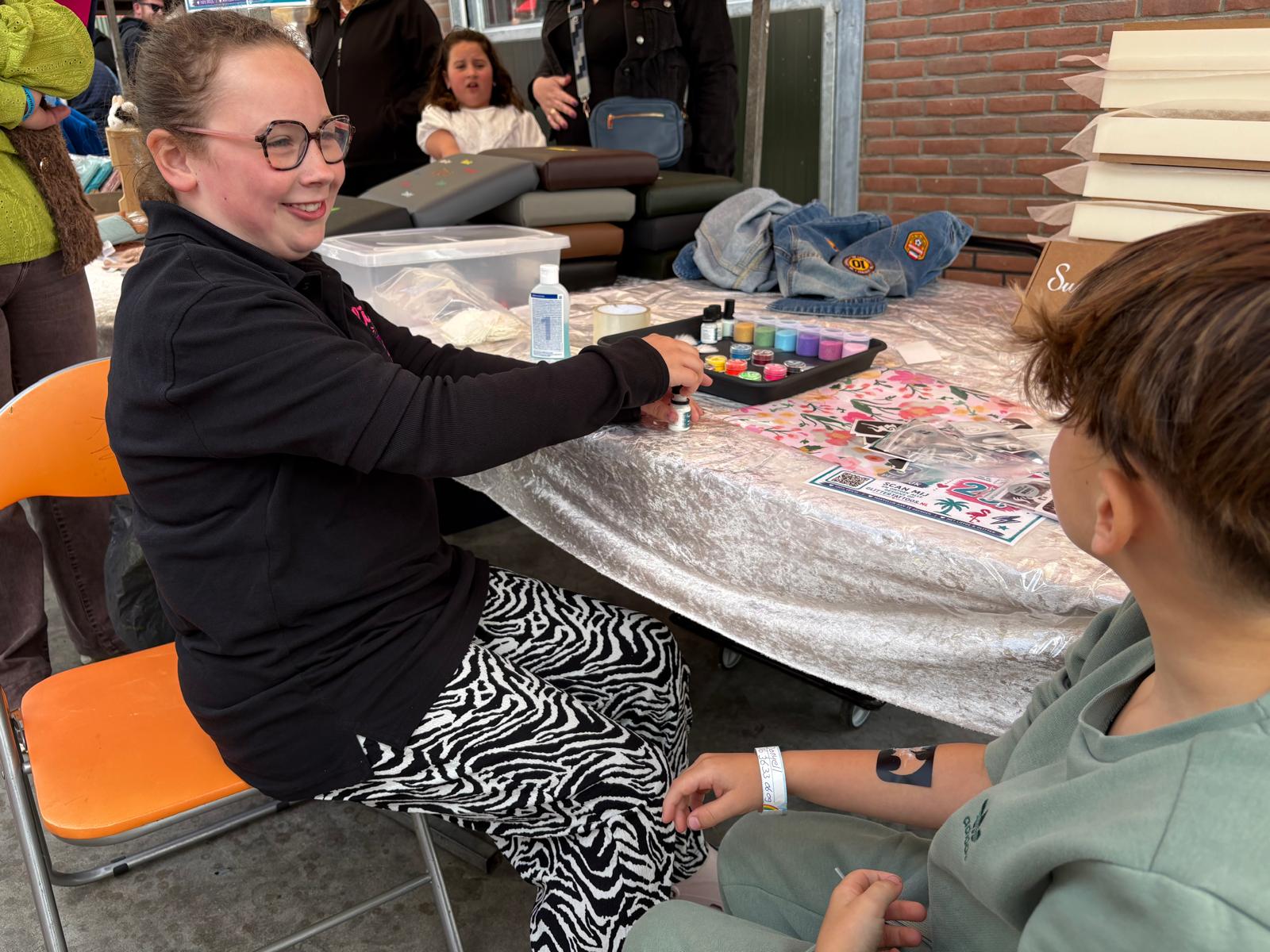 Kind kiest kleuren voor glittertattoos op de Boerendag